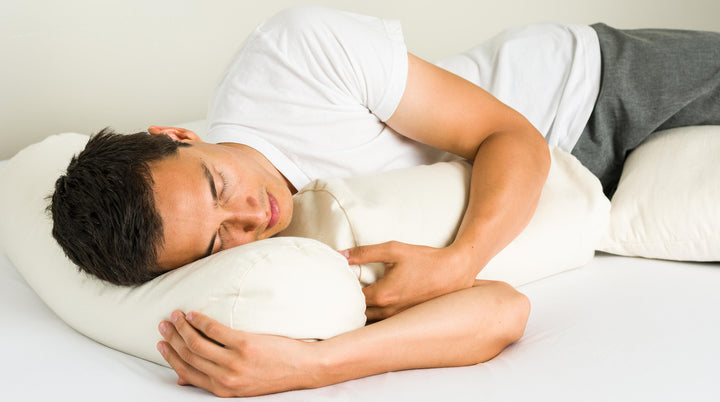 Man sleeping with ComfyComfy cylindrical buckwheat hull pillow naturally cooling breathable organic sleeping